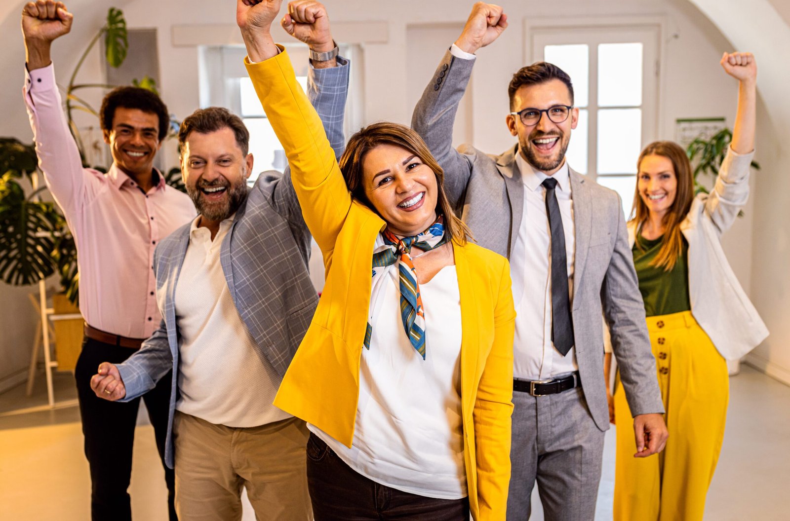 Group of excited business people standing in office.