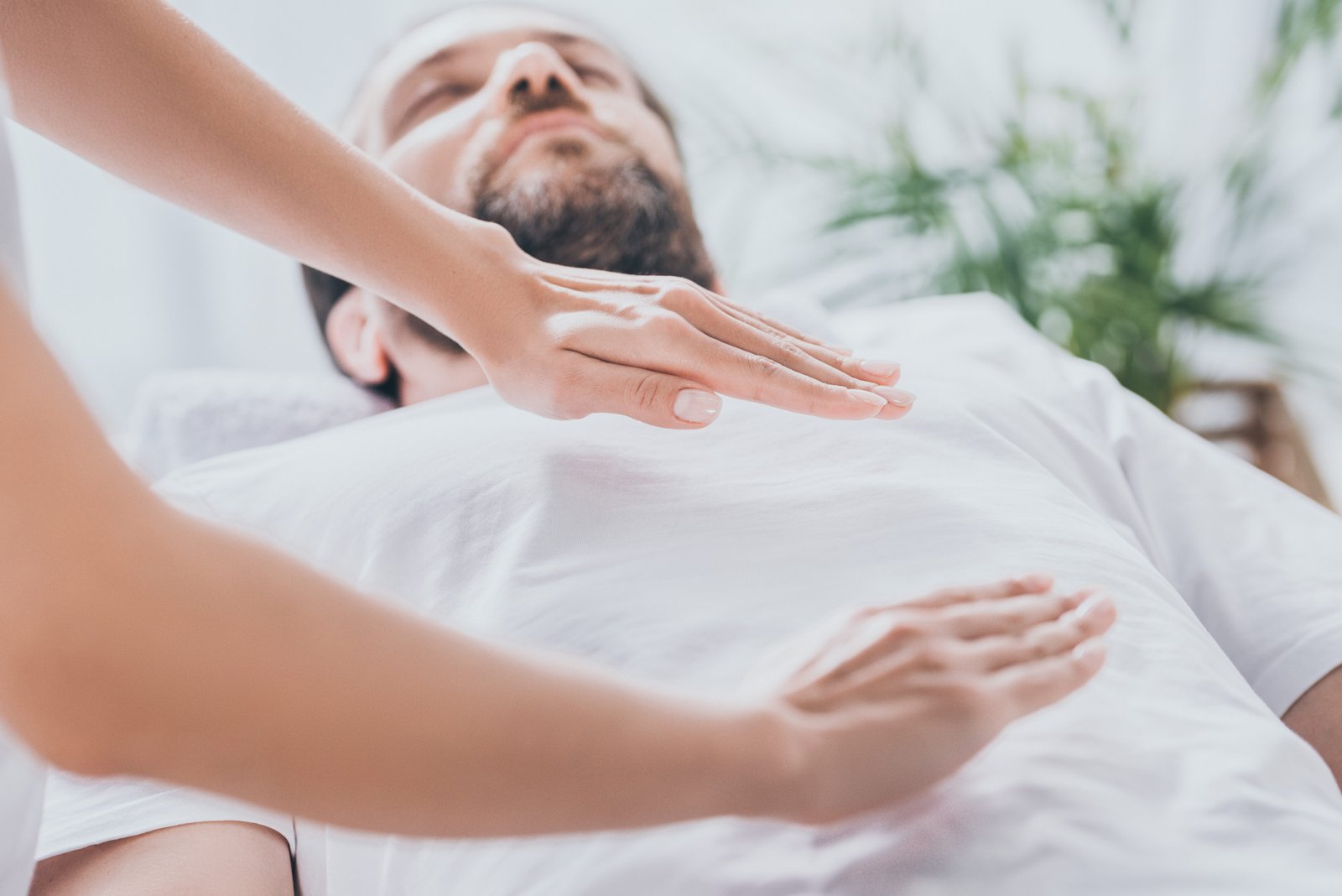 Bearded Man Receiving Reiki Healing from a Master Reiki Healer.